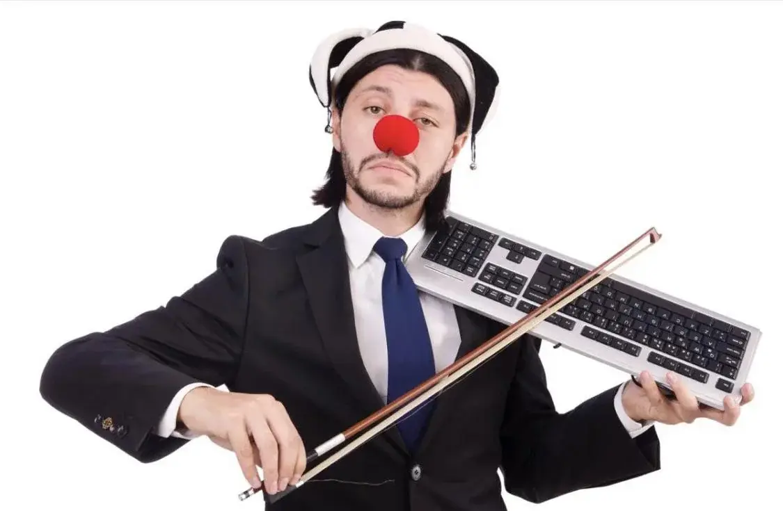 photo of some guy wearing a distinguished suit, a clown nose and a clown hat, playing on a keyboard with a fiddle